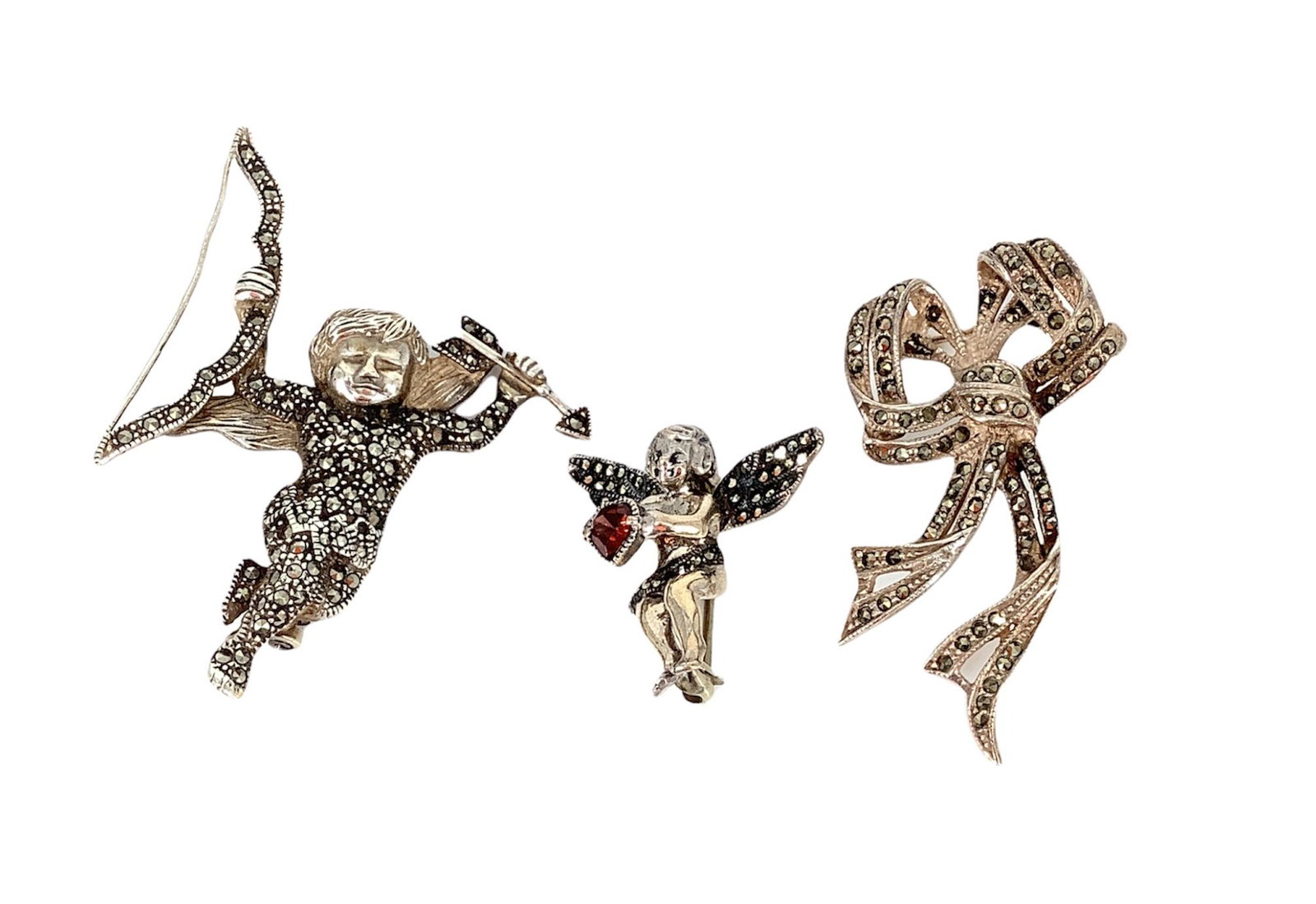 Sterling Silver & Marcasite Pins: Sterling Silver & Marcasite Pins Three in total including two cherub pins one measures 2.35" in height and the other which is holding a gemstone heart (possibly enhanced) 1.10". Lastly this lot includ