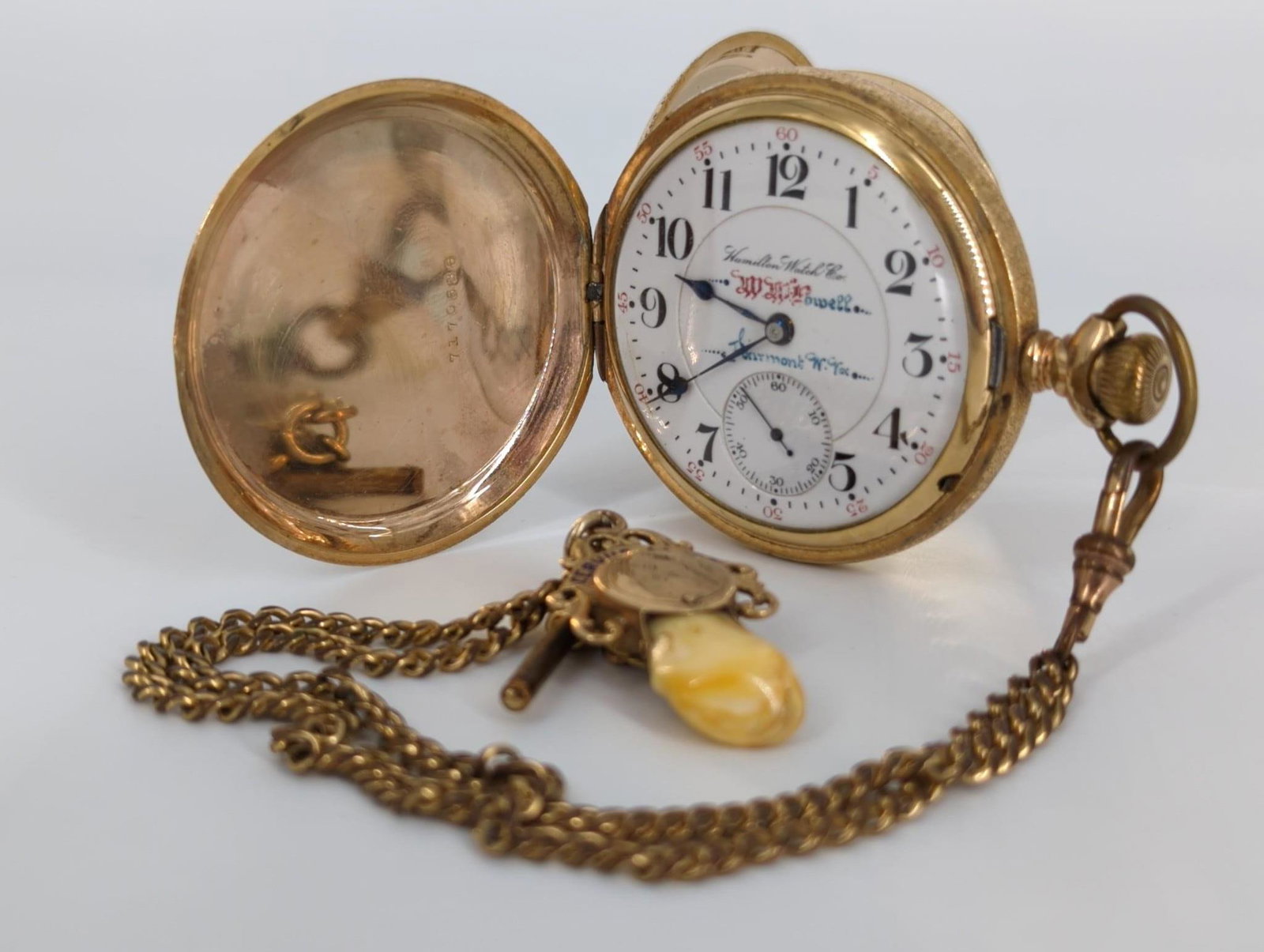 One Gold Tone Pocket Watch (Y/M) With Chain (Y/M) &: One Gold Tone Pocket Watch (Y/M) With Chain (Y/M) & Pendant (Y/M) Hamilton pocket watch with W.M. Powell and Fairmont, West VA on dial. Winds, sets and ticks at time of listing. Hinged, gold-filled 25
