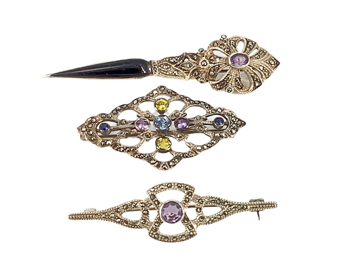 Sterling Silver & Marcasite Pins: Sterling Silver & Marcasite Pins Three pins in total, one measures 2.21" in length with a round cut amethyst center stone, 2" openwork pin with blue, purple & yellow round cut gemstones - likely enhan