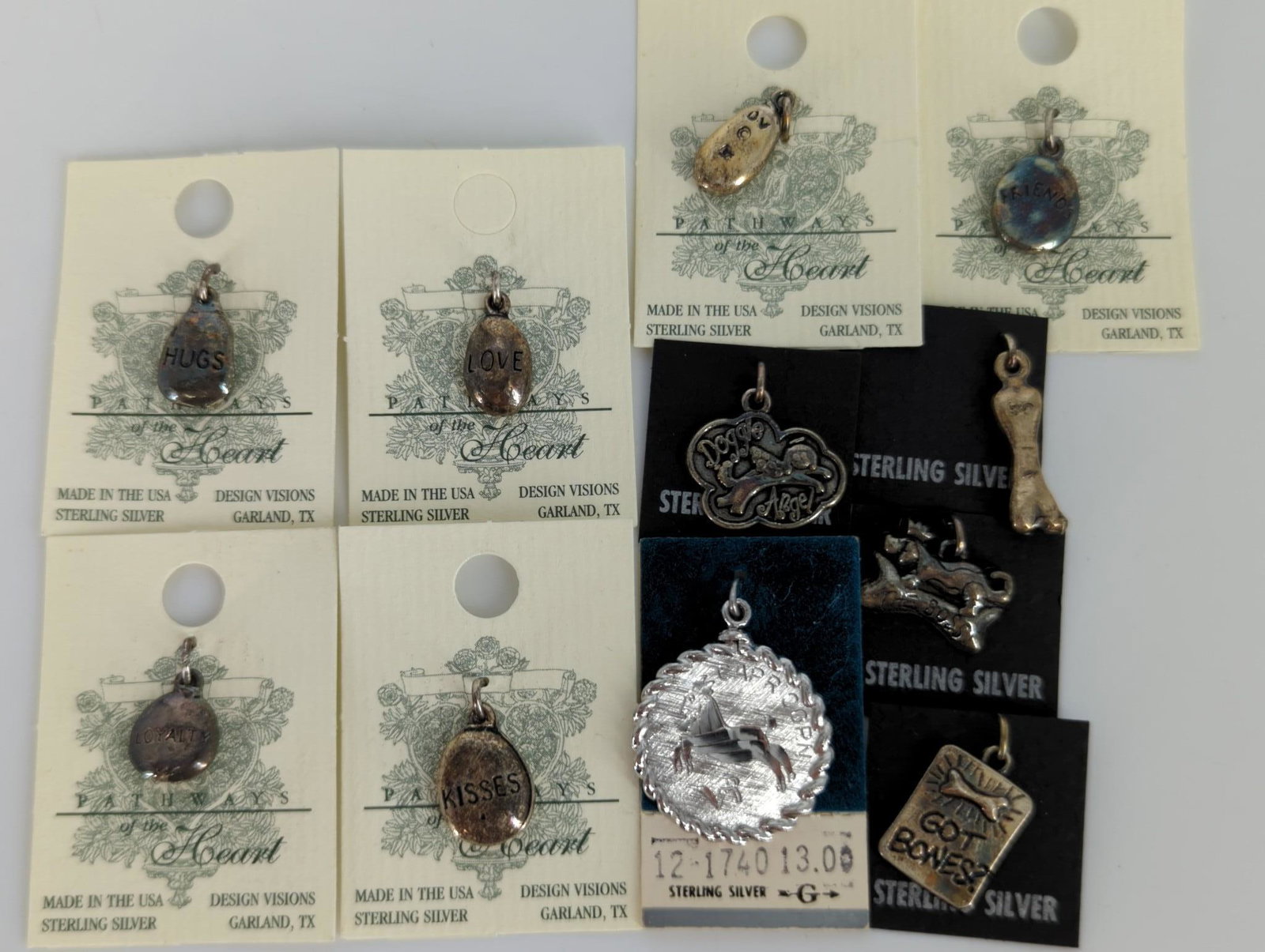 Eleven Assorted Sterling Silver Charms: Eleven Assorted Sterling Silver Charms New old stock on original cards, six with engraved words and four featuring a dog motif including figural and bone motifs. One brushed disk "Capricorn" pendant/c