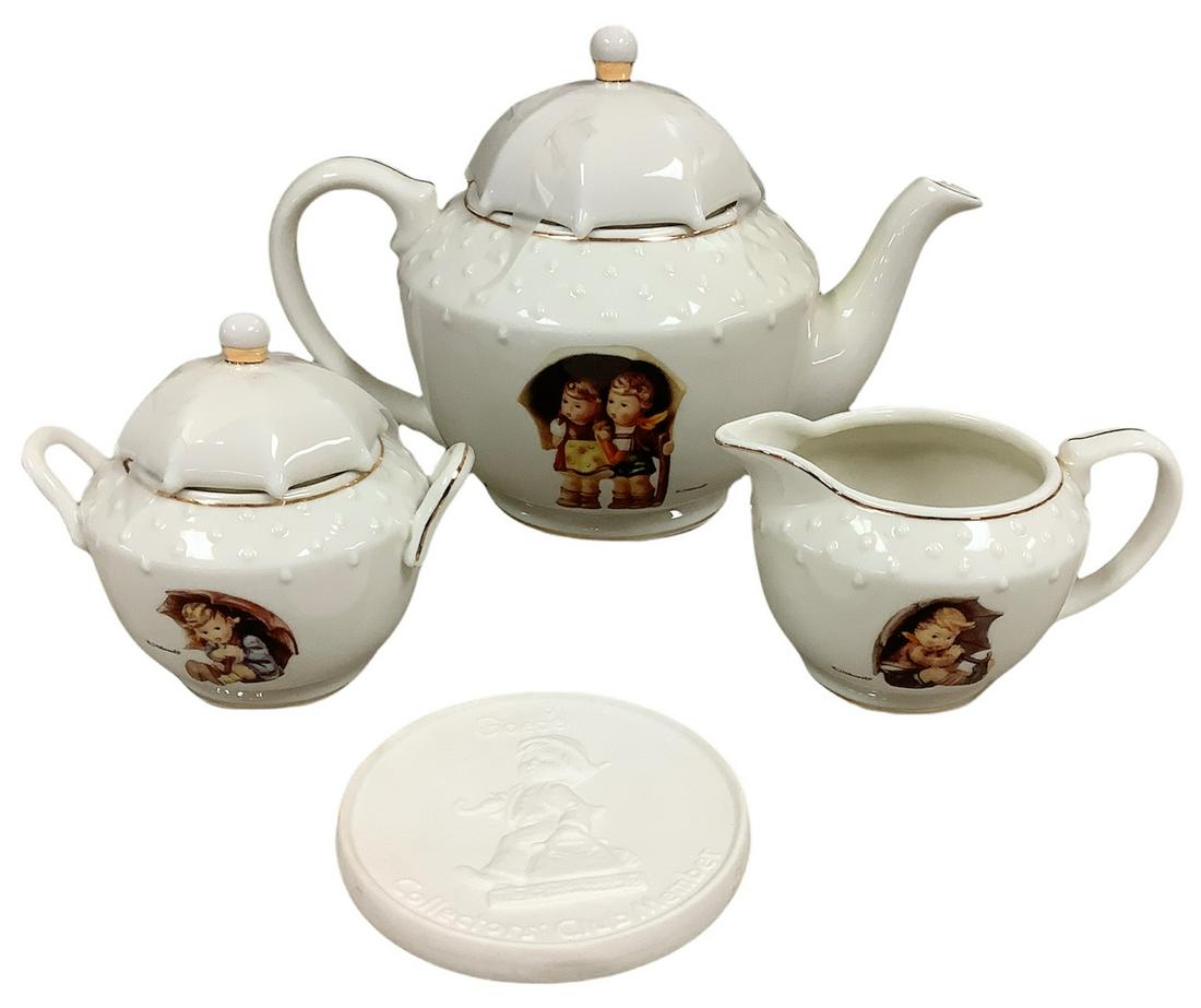 Hummel porcelain tea set including Stormy Weather teapot, Umbrella Girl sugar bowl with lid and: Hummel porcelain tea set including Stormy Weather teapot, Umbrella Girl sugar bowl with lid and Umbrella Boy creamer, all with 23kt gold accents and a bisque Goebel CollectorÃ­s Club plaque.