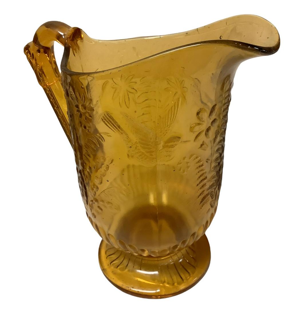 Tall older amber color glass pitcher @ 9" high. Bird & floral motif, some small chips. Bubbles in: Tall older amber color glass pitcher @ 9" high. Bird & floral motif, some small chips. Bubbles in glass.