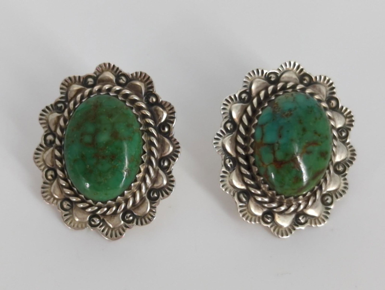 Sterling Silver & Semi-Precious Stone Earrings: Sterling Silver & Semi-Precious Stone Earrings Post back design measuring 0.9” in length featuring a green semi-precious stone in the center, accented with cold chiseled accent as, stamped and t