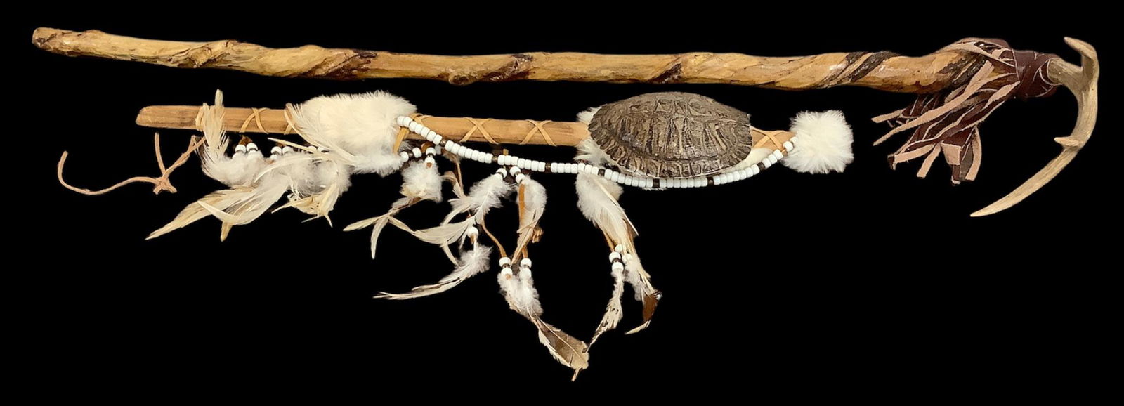 Lot of Native American items including a ceremonial rattle with rabbit fur, turtle shell, feathers: Lot of Native American items including a ceremonial rattle with rabbit fur, turtle shell, feathers and beads, 25"L, and a walking stick made of twisted wood, leather and deer antler, 39"L.