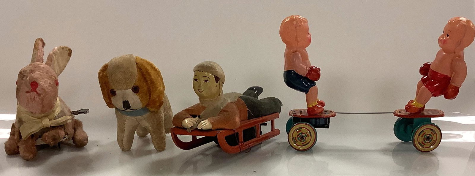 Four vintage toys including a 4" wind-up rabbit and a 4" dog figurine, both marked Japan, a child on (1 of 1)