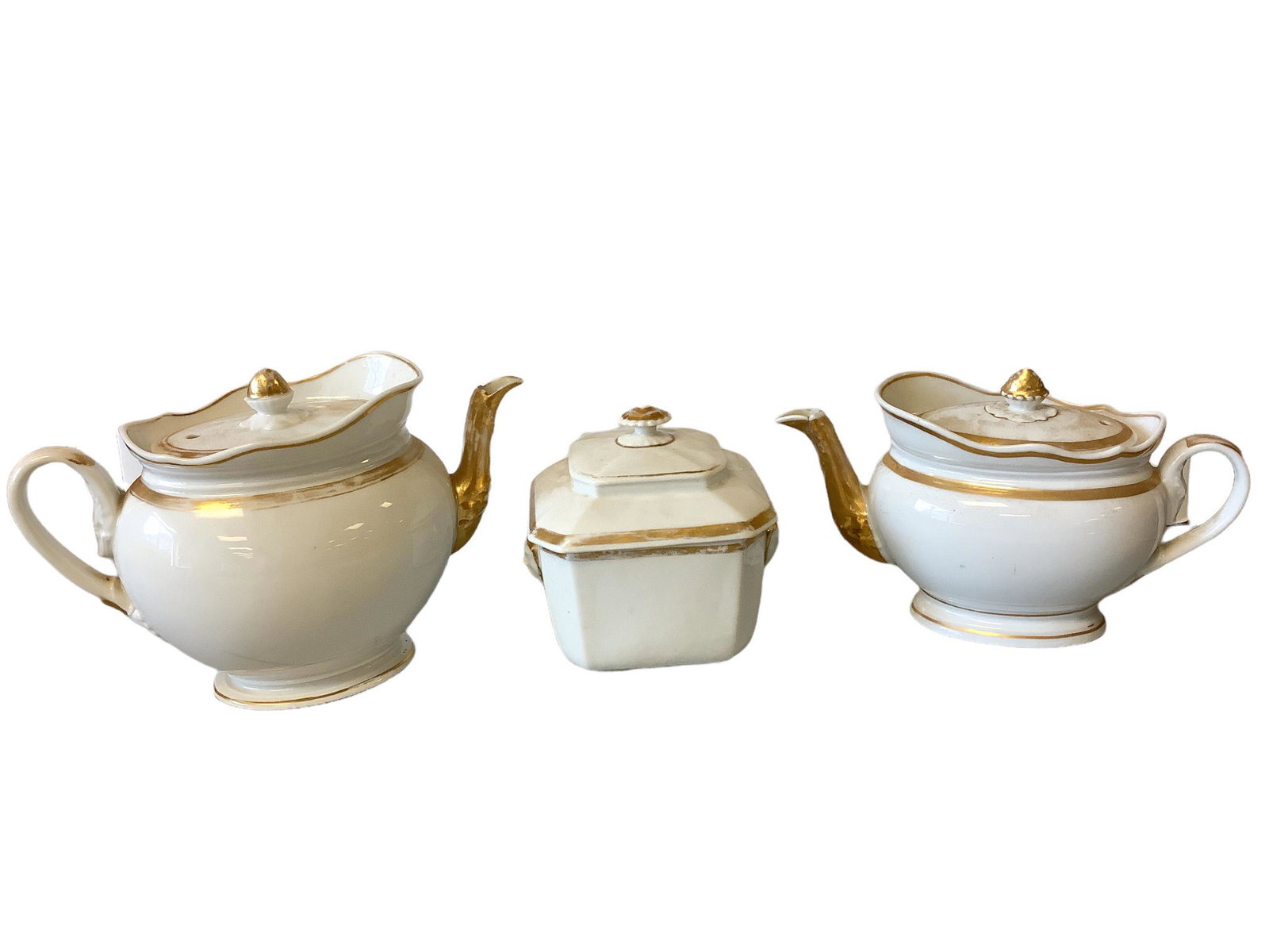Lot of 3 pieces of porcelain including 2 oval teapots and a table sugar that range in height from: Lot of 3 pieces of porcelain including 2 oval teapots and a table sugar that range in height from 8” to 6 3/4” tall. The 2 teapots have damage.