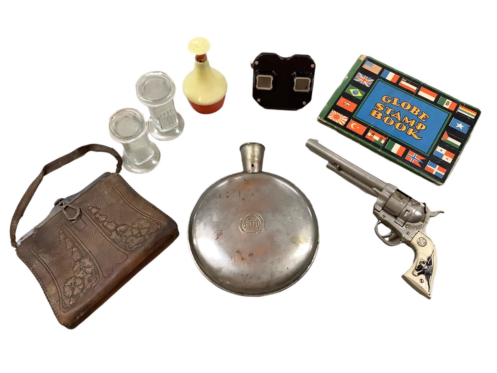 A mixed lot including a metal hot water bottle, a cap gun, Sawyers bakelite view master viewer, a: A mixed lot including a metal hot water bottle, a cap gun, Sawyers bakelite view master viewer, a stamp book, plastic sprinkler bottle and newspapers covering President Kennedyâ€™s assassination.