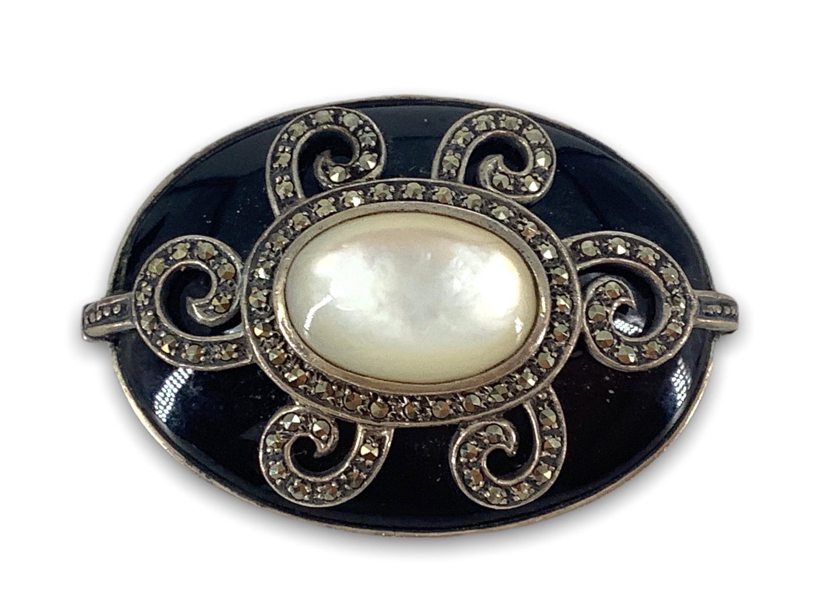 Sterling, Onyx and Marcasite Pin: Sterling, Onyx and Marcasite Pin Stamped and tested, signed, 48.75mm in length, bezel set onyx stone cabochon (oval shape) adorned with marcasite/pyrite stones and white mother of pearl. 0.82 troy oun