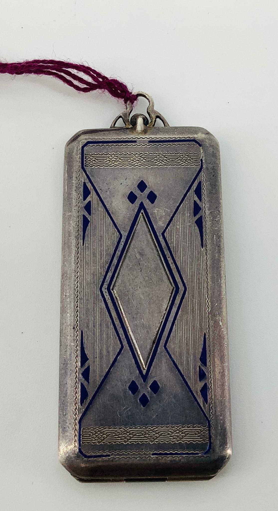 Antique Silver Locket: Antique Silver Locket 0.59 troy ounces tw., 52.0mm x 23.75mm in size, Art Deco style with embossed details and blue enameling, with two photos enclosed, hinged.