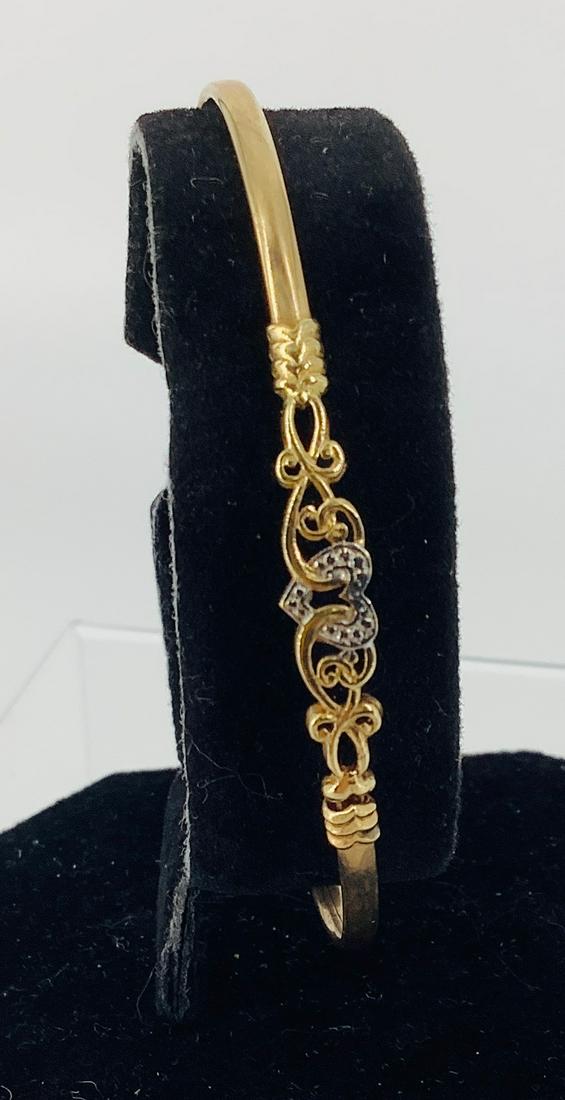 10kt Dual Tone Bracelet: 10kt Dual Tone Bracelet Flexible design with an inner diameter of (2.6Ã®) featuring a heart and scroll motif in the center with a white gold heart, closes near the center design (3.2 grams tw).