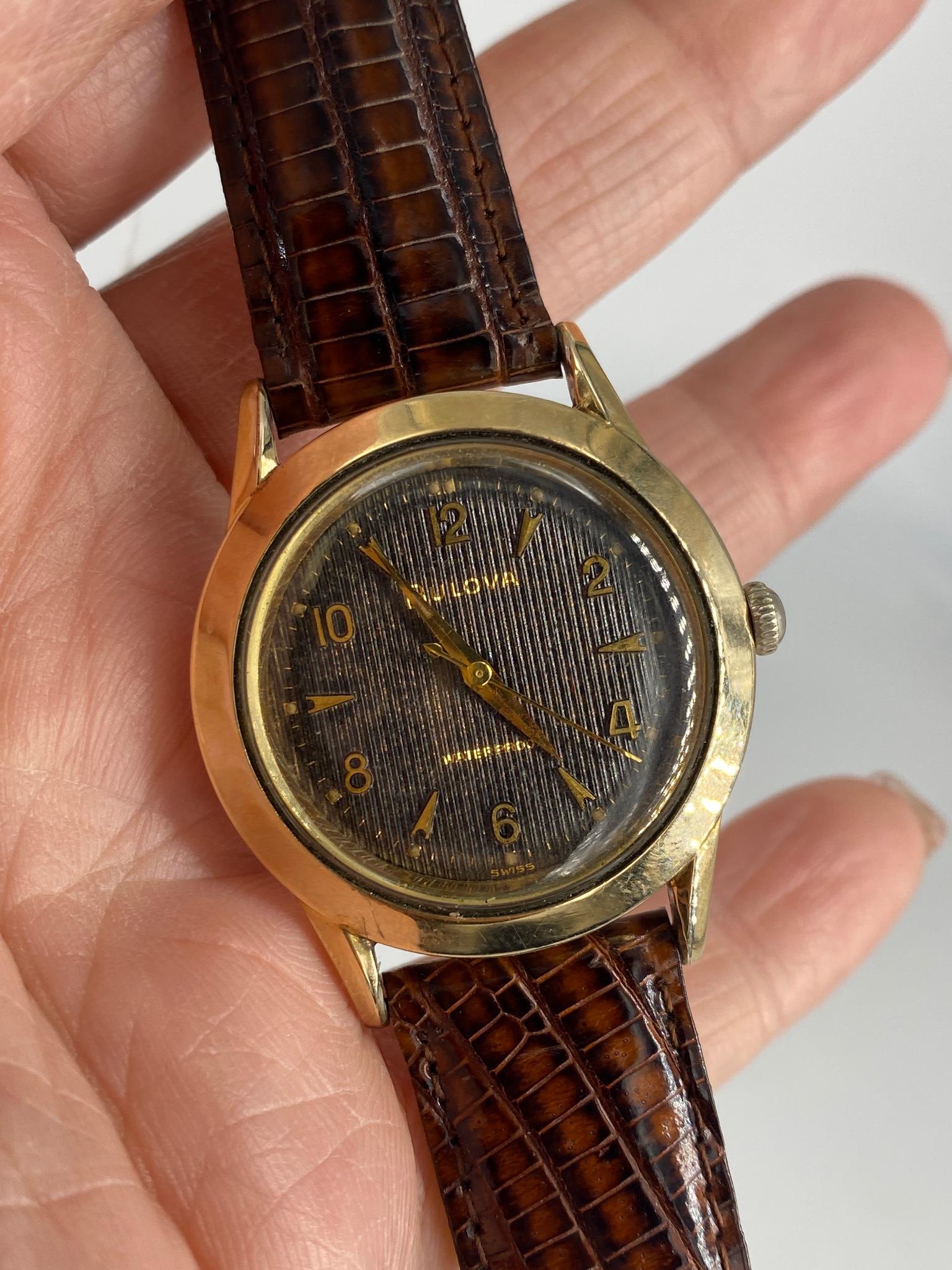 Vintage Bulova Wristwatch with Lizard Strap: Vintage Bulova Wristwatch with Lizard Strap 10kt Yellow gold R.G.P. Bezel containing a water proof / shock resistant #D178776, the lizard band measures approx. 8.25" in lenght - Maxm the dial measures
