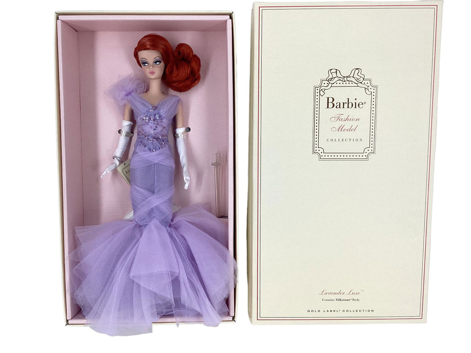 BFMC LAVENDER LUXE SILKSTONE BARBIE. Barbie has red hair pulled into a side ponytail wearing a fab: BFMC LAVENDER LUXE SILKSTONE BARBIE. Barbie has red hair pulled into a side ponytail wearing a fab gown of lavender tulle, white gloves, shoes. A gold label Barbie has no more than 8,100 worldwide.