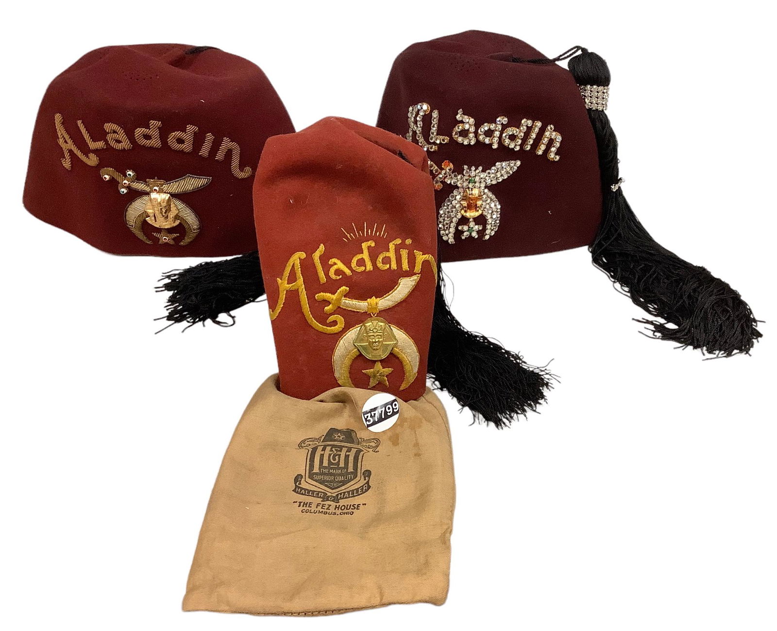 Lot of 3 Aladdin tasseled felt fezzes. All in good condition with undamaged emblems. Two with the: Lot of 3 Aladdin tasseled felt fezzes. All in good condition with undamaged emblems. Two with the rhinestone dagger tassel clasp. One with storage bag from Haller & Haller “The Fez House”