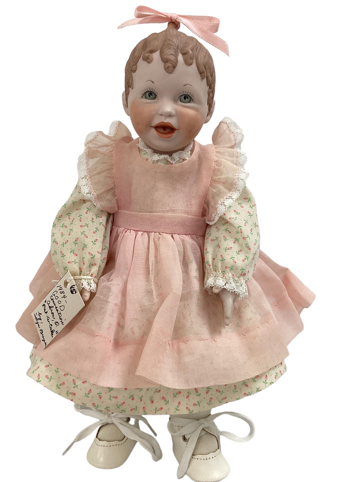 13" bisque "Pat-A-Cake" doll by Sonja Breyer for 1984 convention. Painted hair, painted eyes and: 13" bisque "Pat-A-Cake" doll by Sonja Breyer for 1984 convention. Painted hair, painted eyes and facial features, open mouth, she's wearing a ribbon in her hair, pink, white and green dress with a pet