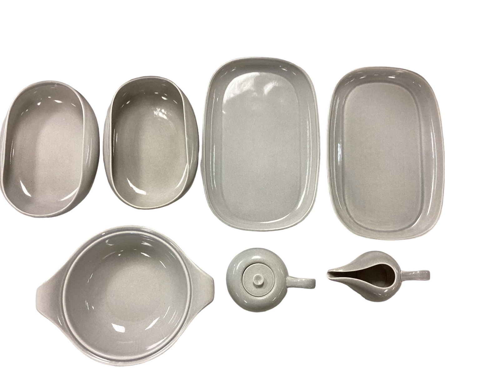 Russel Wright by Steubenville Mid-Century Serving Pieces: (7) light gray pieces, including creamer & covered sugar, (2) serving trays, and (3) serving bowls.Shipping Note: $65.00 packing and materials fee plus actual carrier costs.