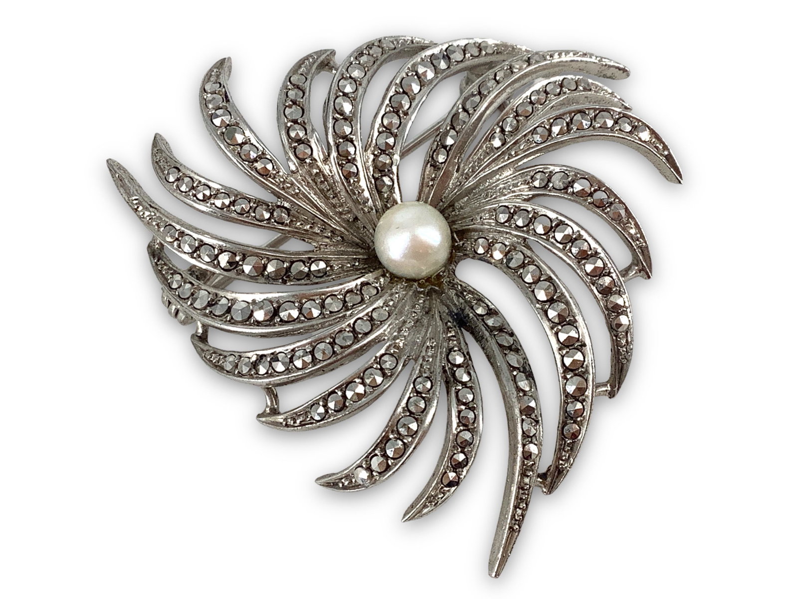 Sterling Silver Pearl Brooch: Sterling Silver Pearl Brooch Measuring (1.72”) in diameter, radiating design featuring a (5.8mm) pearl center stone, accented with marcasite stones, stamped and tested (0.37 troy oz tw).