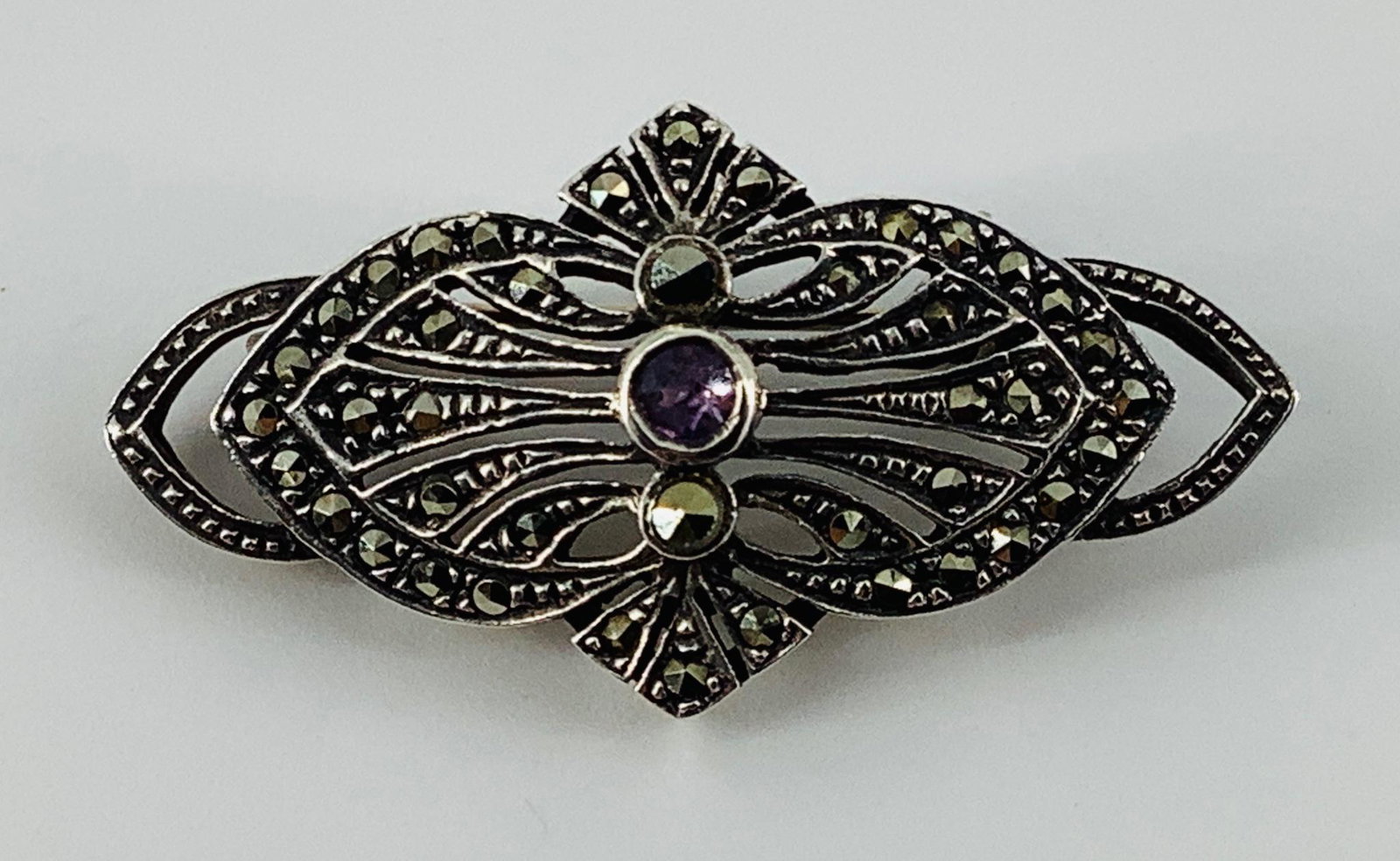 Sterling and Amethyst Stone Pin: Sterling and Amethyst Stone Pin Stamped and tested 925/sterling silver, 3.9 dwt., 38.25mm in length, openwork design with marcasite adornments, set with 3.0mm amethyst stone round at center (pale body
