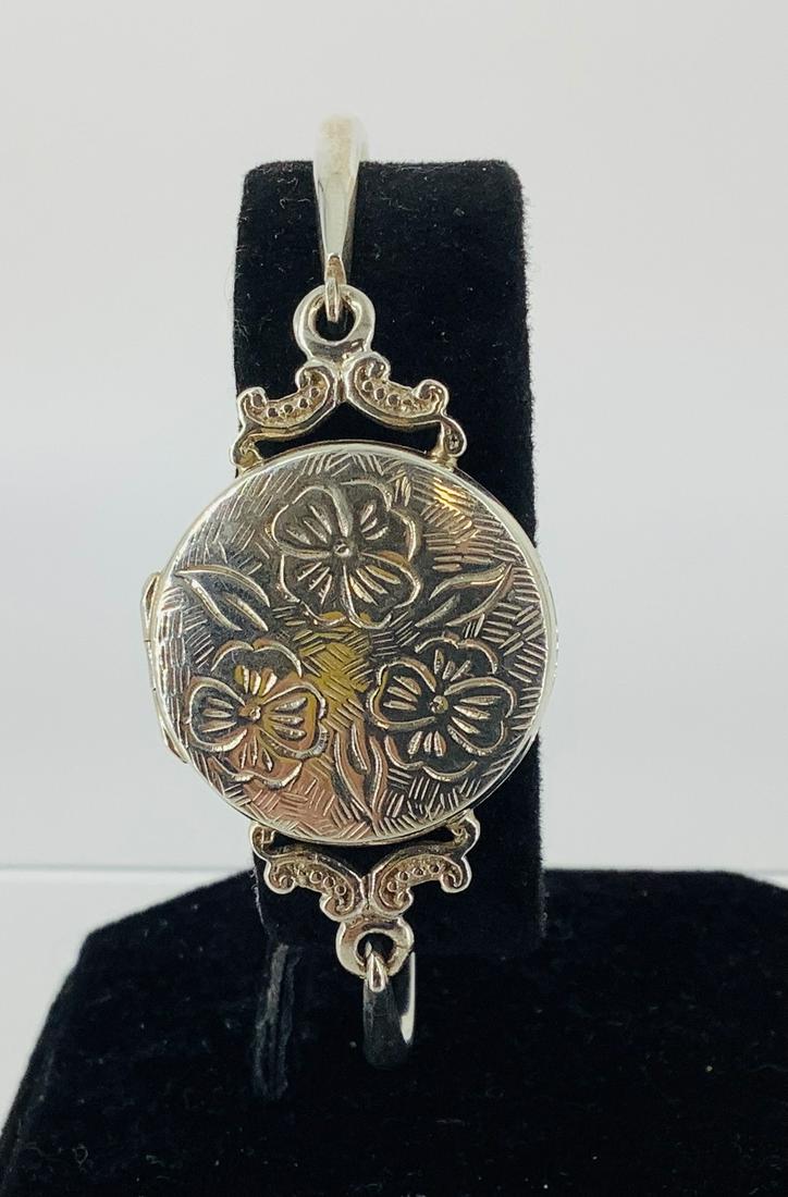 Sterling Bracelet With a Locket Style Center: Sterling Bracelet With a Locket Style Center Hook style front closure near the locket center, with an inner diameter of (2.45”) featuring a reposè floral design (0.47 troy oz tw).