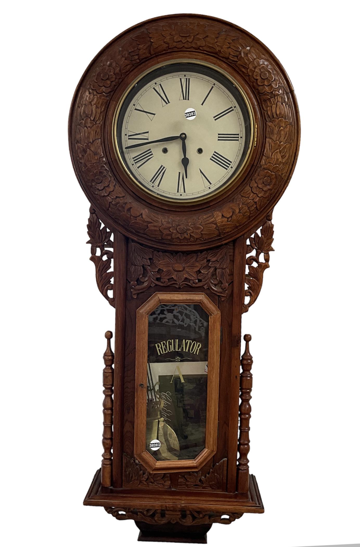 Regulator Wall Clock: Regulator Wall Clock Measuring approx (50î x 21î) key, pendulum and book included, loose inside, Roman numeral indicators, hand carved floral adornments.
