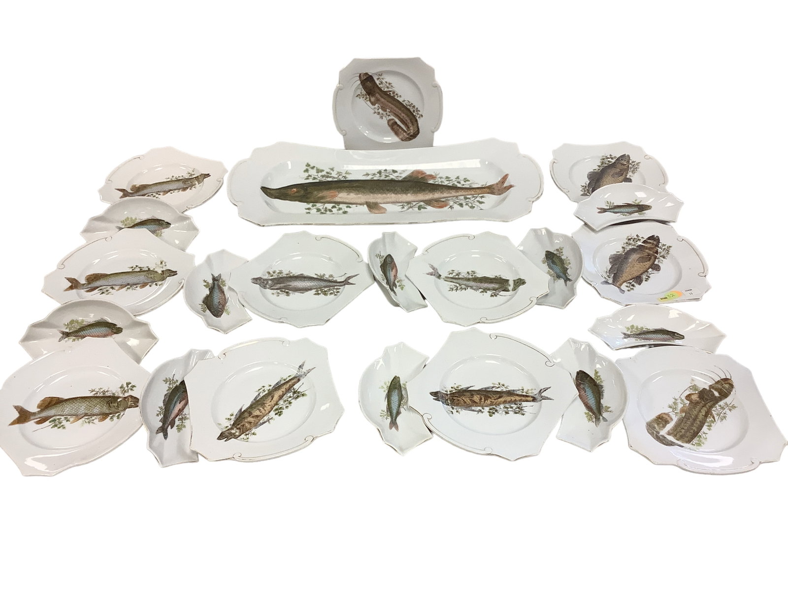 Fantastic Fish Serving Set: Gold rimmed fish plate 21.5”Lx10”W. Gold edge is worn.Eleven 7.5”x8” fish plates. Gold edge is worn.Ten 7.5”Lx3”W bone dishes. One dish is cracked (see photo). Gold