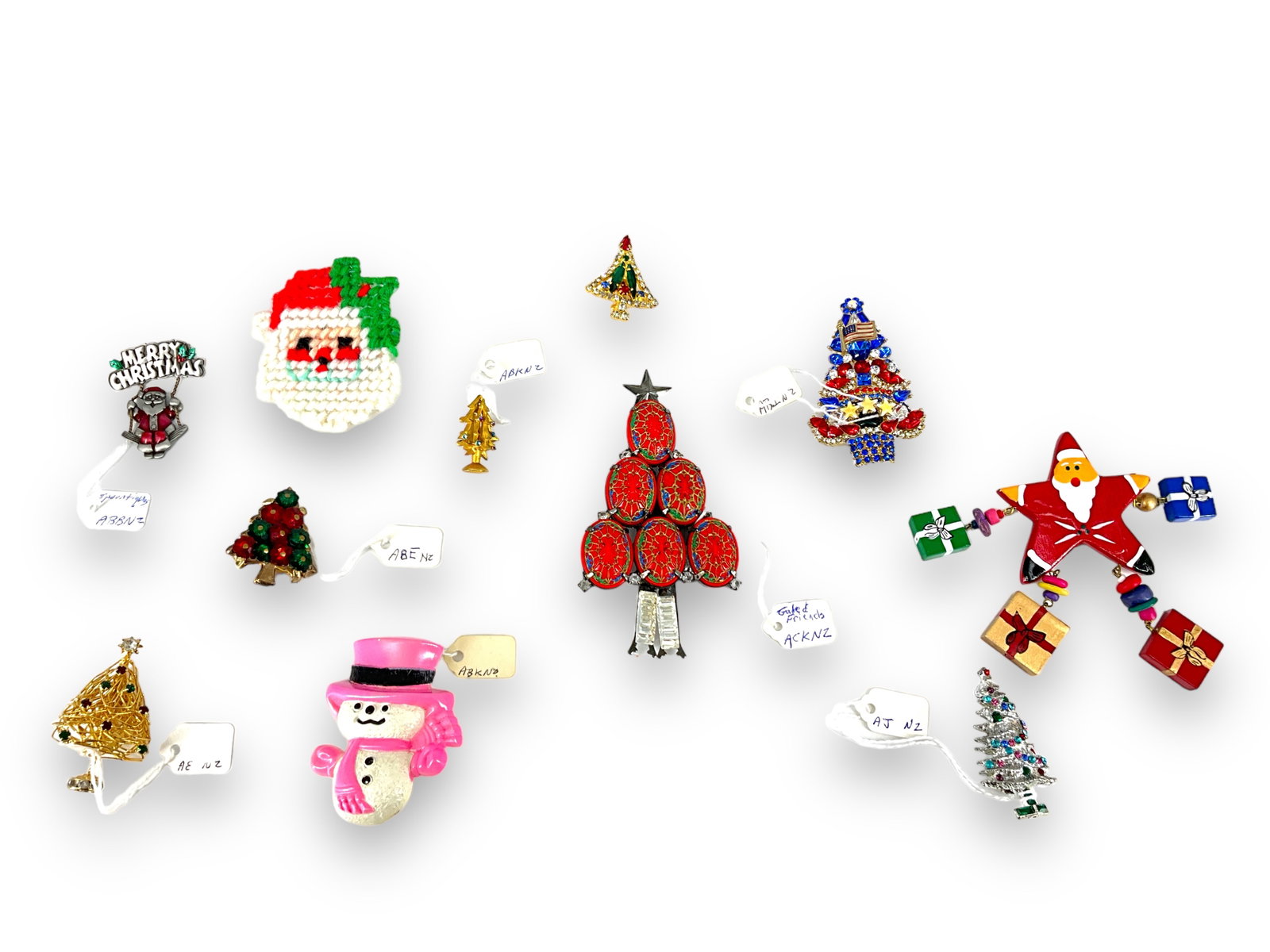 Assortment of Eleven Holiday Pins: Assortment of Eleven Holiday Pins Two signed (Spoontiques and Avon) - remainder unsigned, eleven in total, measuring up to 107.0mm in height. Designs including Santa, snowman and Christmas tree motifs