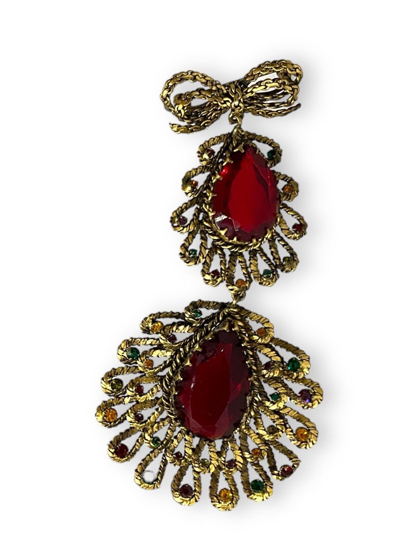 Darling Two-Tier Peacock Style Pendant: Darling Two-Tier Peacock Style Pendant Brass toned Brooch measuring (4.25" in length) with a double chain bow at the top accented with two oversized red fashion crystals in peacock stylized settings w