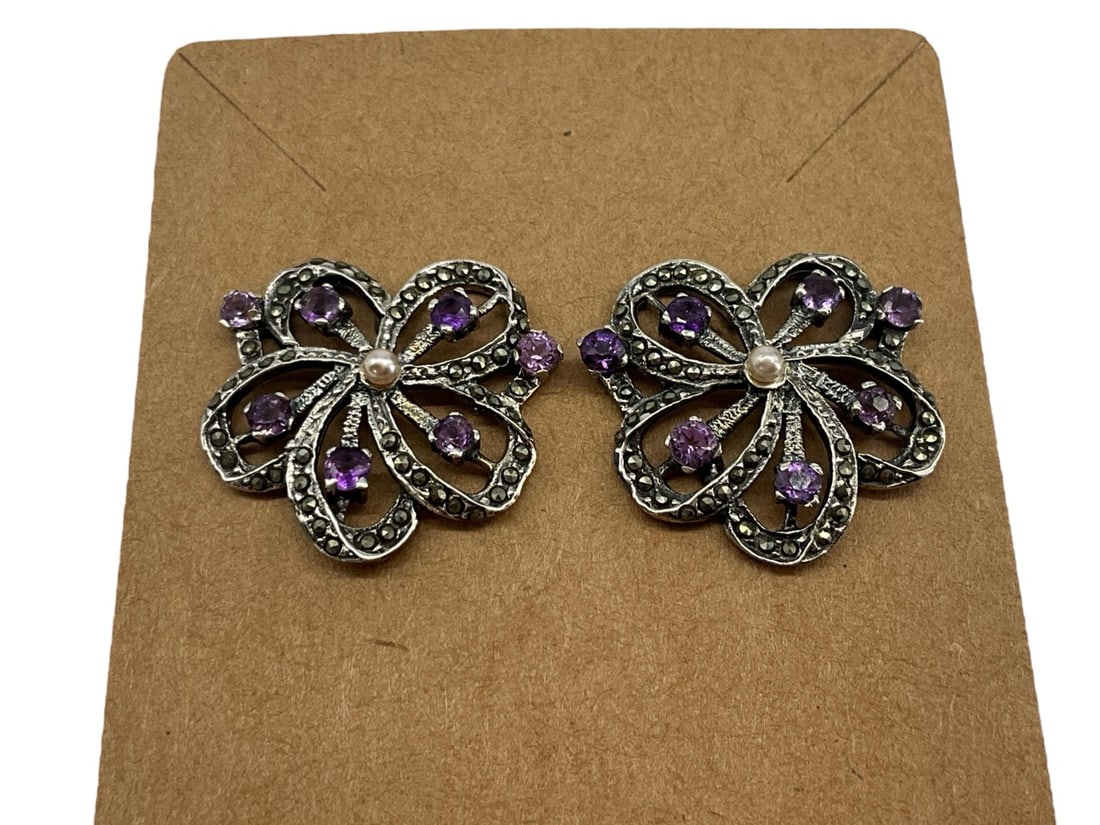 Sterling Silver Post Back Earrings: Sterling Silver Post Back Earrings Floral design with a seed pearl center stone surrounded with small amethyst stones and marcasite adornments, stamped and tested (0.22 troy oz tw).