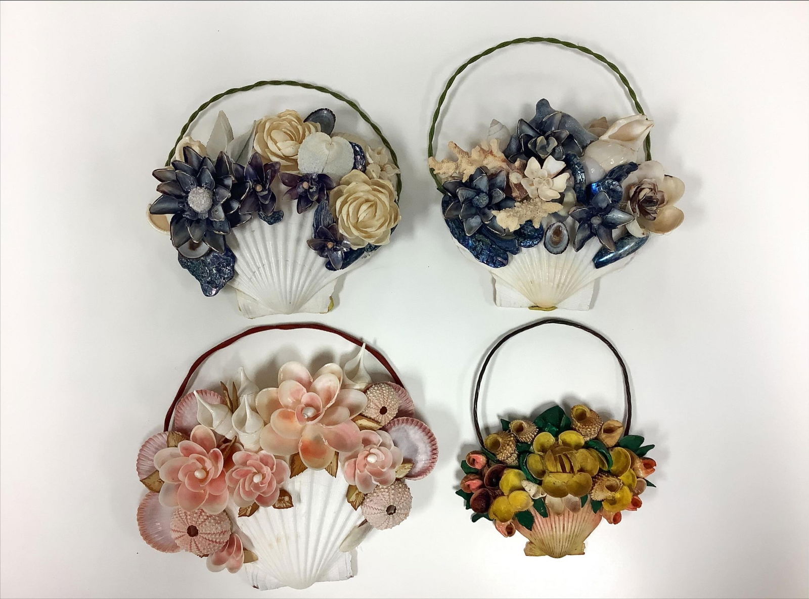 Four Crafted Flower Basket Wall Decorations: Four Crafted Flower Basket Wall DecorationsThese are handmade crafts of seashells, some of which have been painted, to create decorative baskets of flowers. Baskets measure 7-8" tall. There is some wr