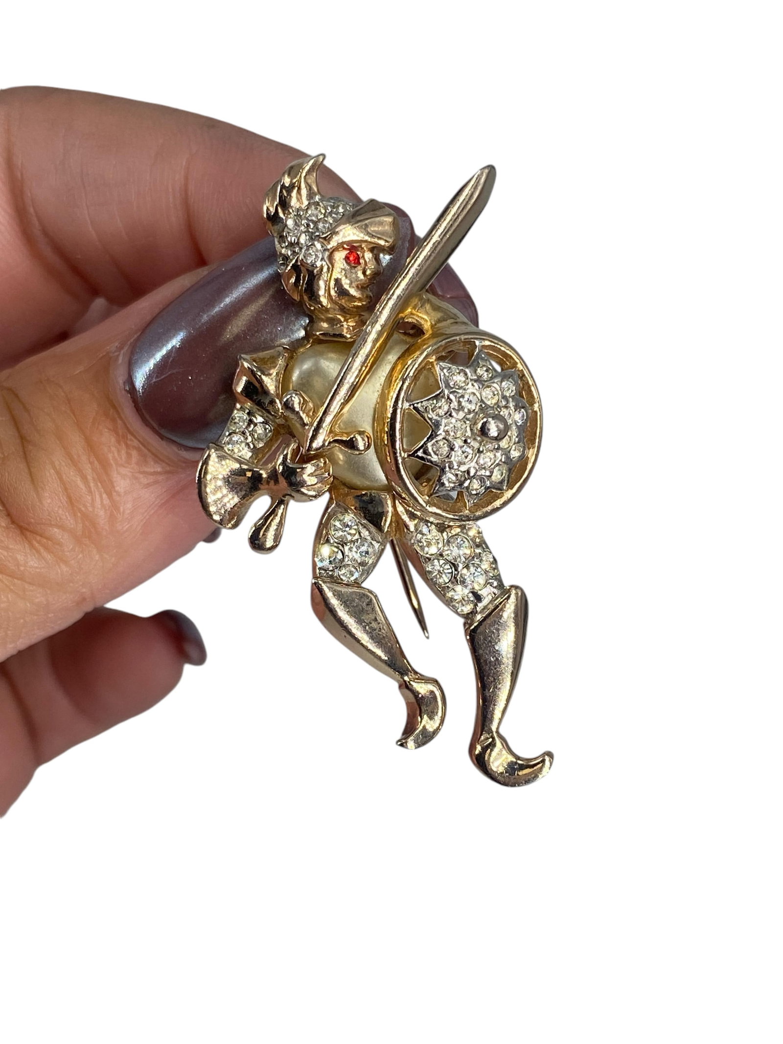 Hallmarked Vintage "Reja" Knight Brooch: Hallmarked Vintage "Reja" Knight Brooch Vintage brooch is in gold-tone metal and designed as a knight with a sword and shield, has diamantÈ accents, is approx 2" tall and hallmarked "Reja."