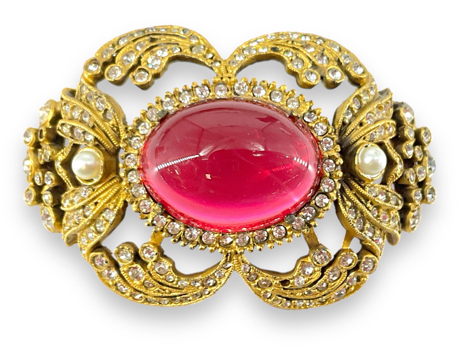 Cadoro Brooch: Cadoro Brooch Gold tone base medal design measuring (2.45" x 1.6") with clear fashion crystals - two missing, two faux pearls and one jelly belly style cabochon in the center measuring (24.7mmx. 18.3m