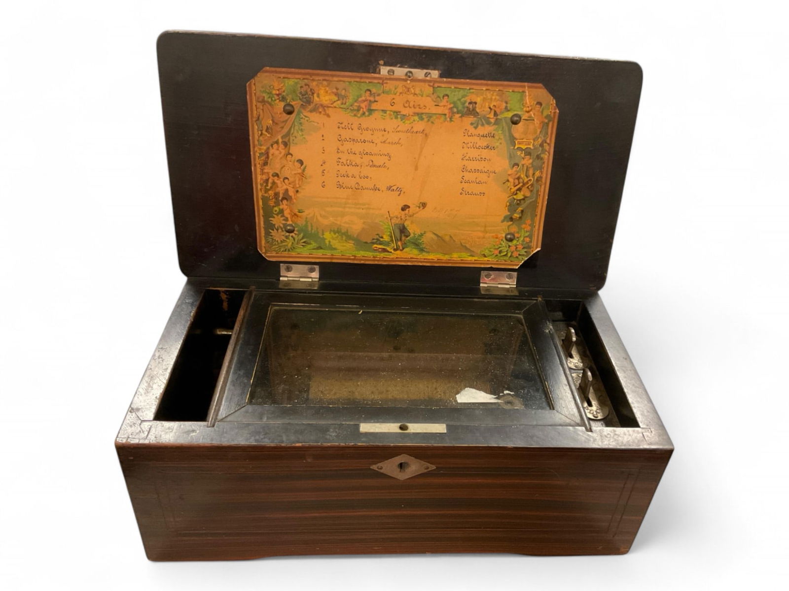 4.5" Cylinder Wood Music Box Approximately 11": 4.5" Cylinder Wood Music BoxWooden music box. Label inside. Nice detail! Plays six tunes. One tooth is missing. Plays at time of cataloging.Approximately 11"