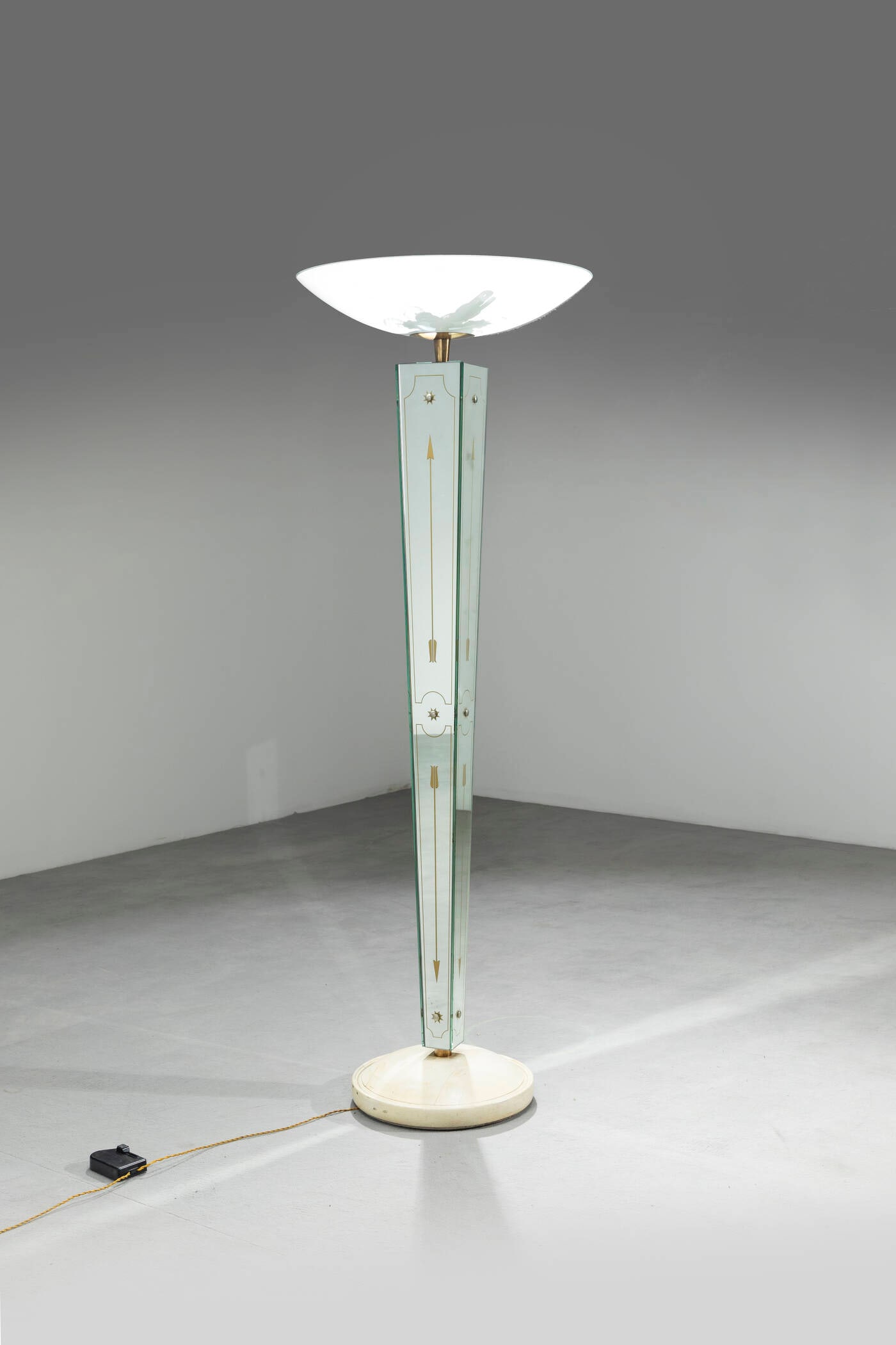 EMILIO LANCIA: EMILIO LANCIALampada da terraStruttura in ottone, elementi in vetro specchiato serigrafato, diffusore in vetro e particolari in ottone.Base in legno verniciatoAnni '40h cm 178x62,5Difetti sulla base