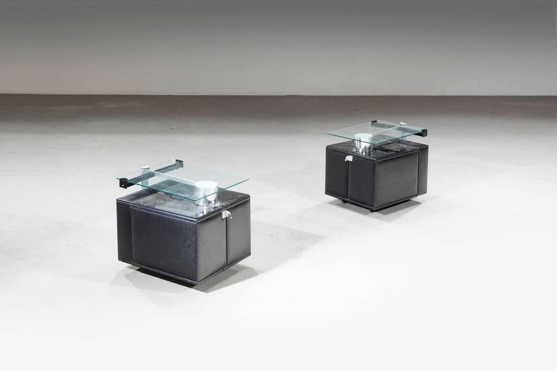 PRODUZIONE ITALIANA: PRODUZIONE ITALIANA Coppia di comodini Struttura in legno rivestito in skai, alluminio e acciaio, piano in vetro e vetro specchiato. Anni '70 cm 46x52x41 Difetti