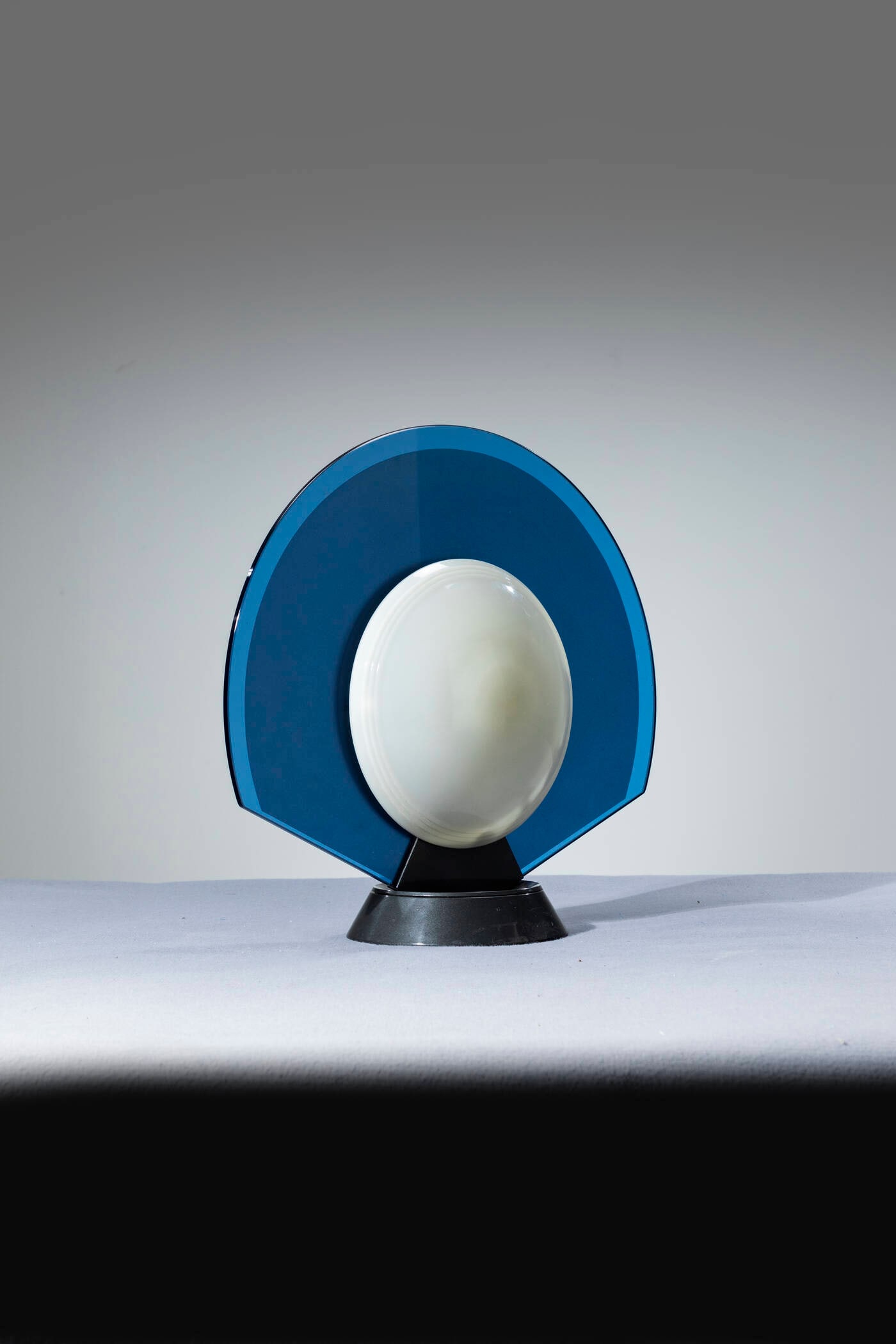 PIER GIUSEPPE RAMELLA: PIER GIUSEPPE RAMELLA Lampada da tavolo mod. TIKAL Vetro blu traslucido e diffusori in plastica. Base in acciaio e girevole. Prod. Arteluce, anni '50 h cm 46x50 Piccoli difetti