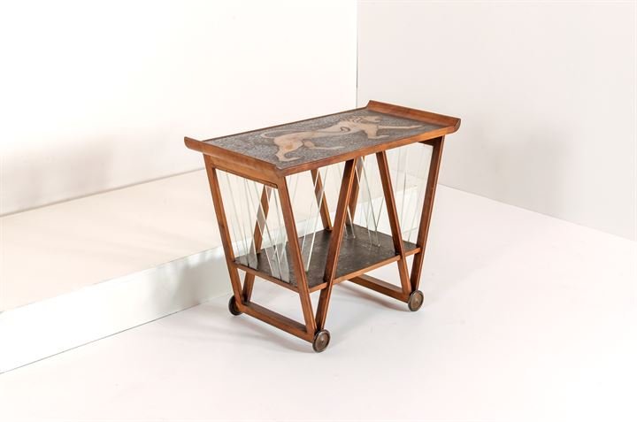 PRODUZIONE ITALIANA: Carrello in legno tinto con piano superiore decorato con figura di leone, inserti in vetro molato. Anni '40 cm 67x45x90