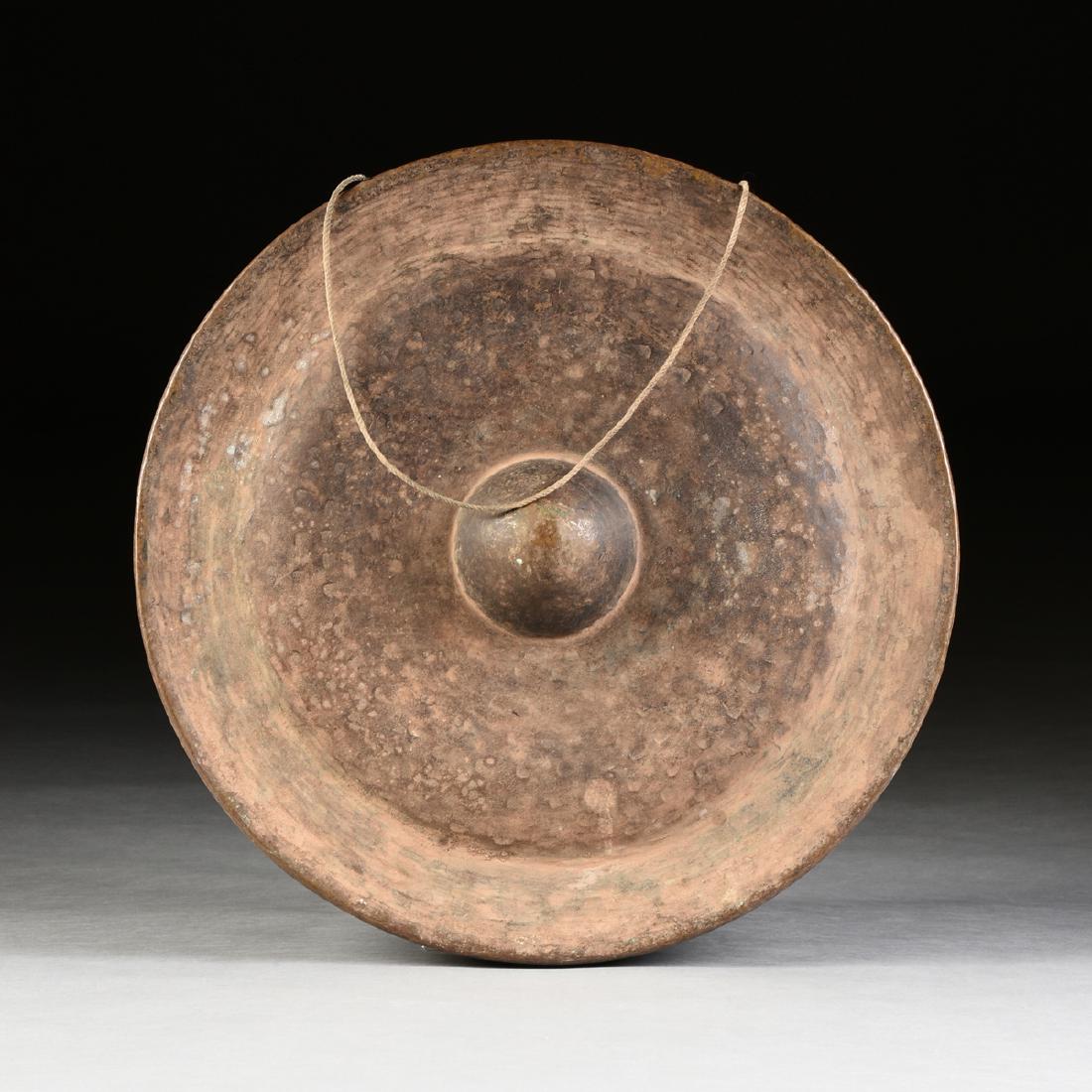 AN ANTIQUE EAST ASIAN HAND FORGED BRONZE PATINATED: AN ANTIQUE EAST ASIAN HAND FORGED BRONZE PATINATED BRASS NIPPLE GONG, 19TH/20TH CENTURY, of circular form centering a protruding boss. Depth: 4" Diameter: 22"
