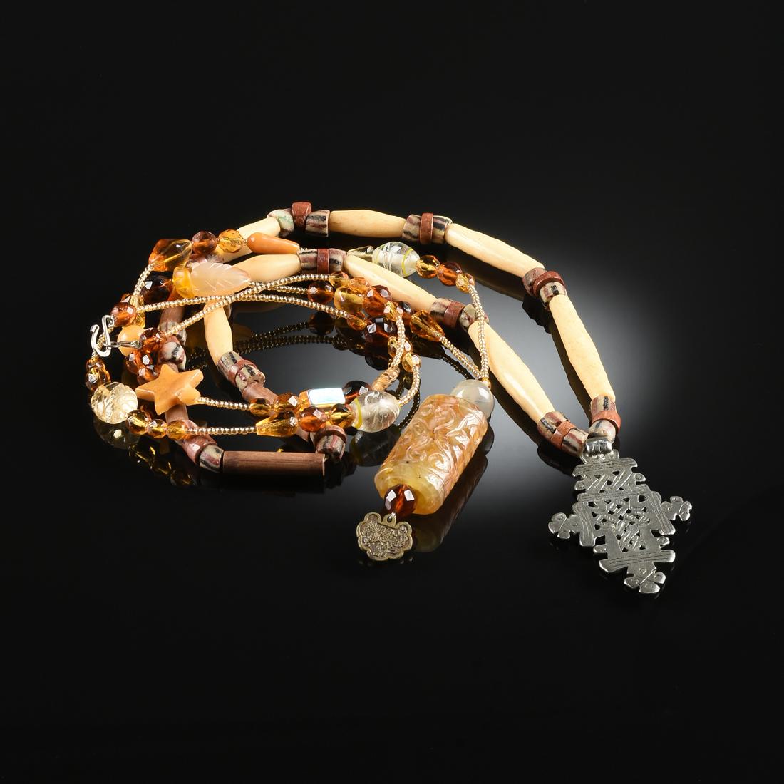 A GROUP OF TWO PRIMITIVE STYLE BEADED FASHION: A GROUP OF TWO PRIMITIVE STYLE BEADED FASHION NECKLACES, MODERN, comprising an African style necklace strung with bamboo, clay trade beads, bone and red coral, centering a pierced Ethiopian Coptic cro
