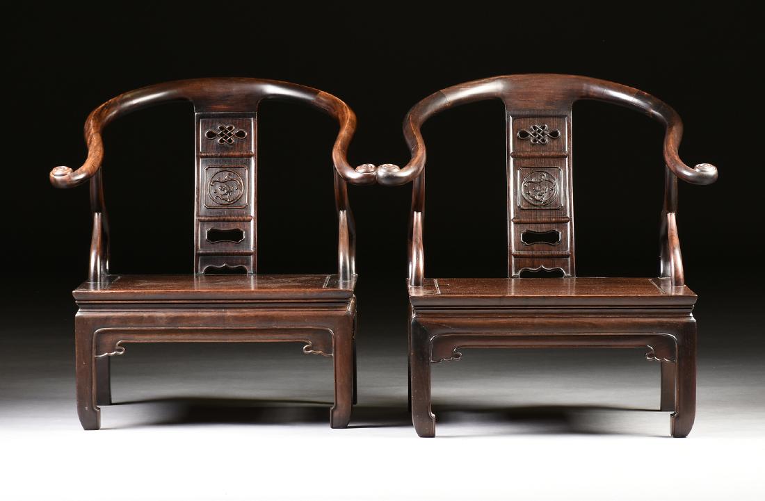 A PAIR OF CHINESE MING DYNASTY STYLE CARVED HONGMU: A PAIR OF CHINESE MING DYNASTY STYLE CARVED HONGMU HORSESHOE ARMCHAIRS, modern, the curved backs over a single vertical splat carved with a pierced endless knot over a dragon motif, above square seats