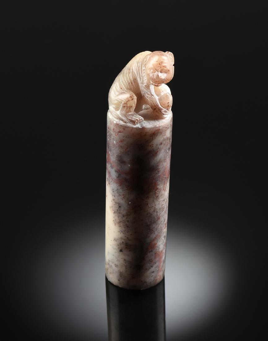 A CHICKEN BLOOD STONE SEAL, POSSIBLY CHINESE,: A CHICKEN BLOOD STONE SEAL, POSSIBLY CHINESE, the seated monkey figure, holding a peach, carved in the round, over an off white, gray, cinnabar red, and black spotted cylinder, terminating in carved c