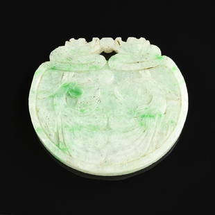 A CHINESE CARVED CELADON APPLE GREEN FLECKED JADE: A CHINESE CARVED CELADON APPLE GREEN FLECKED JADE PENDANT, MODERN, of circular blade form and centering stylized phoenix details, pierced for suspension and surmounted by the pearl flanked by scaly