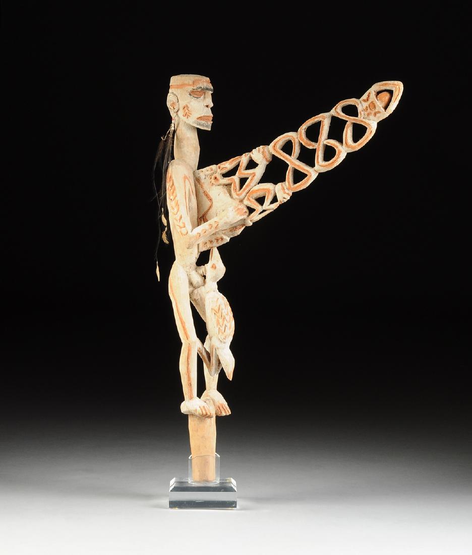 AN INDONESIAN TRIBAL PAINTED AND CARVED WOOD CANOE: AN INDONESIAN TRIBAL PAINTED AND CARVED WOOD CANOE FIGUREHEAD, ASMAT PEOPLES, PAPUA NEW GUINEA, with a flat topped head and short hairstyle above deep angular blackened eyes and a slightly opened mout