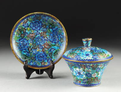 A CHINESE BLUE GROUND CLOISONNÉ COVERED DISH AND: A CHINESE BLUE GROUND CLOISONNÉ COVERED DISH AND UNDERPLATE, LATE 20TH CENTURY, each piece polychrome enameled throughout with "1,000 Blossoms" decoration and comprising; a flaring circular bowl with