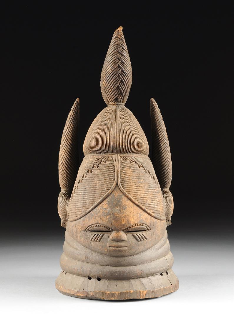 A MENDI CARVED WOOD CEREMONIAL HELMET MASK, SIERRA: A MENDI CARVED WOOD CEREMONIAL HELMET MASK, SIERRA LEON, of hollow form with an elaborate combed and braided hairstyle, over a rounded forehead and deep stylized eyes above scarification cheek details