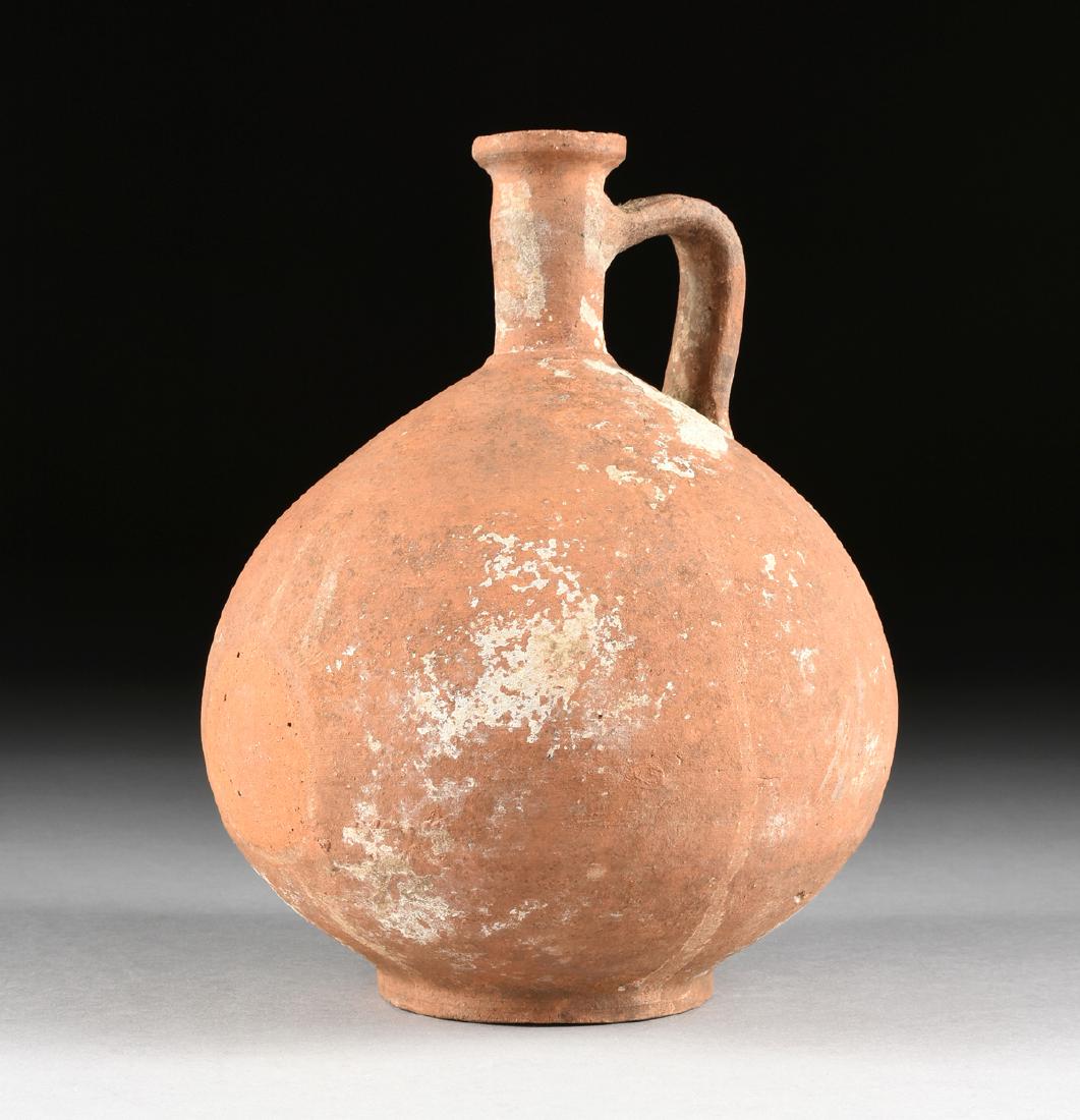AN ANCIENT ROMAN TERRA SIGILLATA WINE JUG, POSSIBLY: AN ANCIENT ROMAN TERRA SIGILLATA WINE JUG, POSSIBLY CYPRIOT, CIRCA 1ST CENTURY AD, matte red slip painted buff clay, wheel made, the round, everted rim over a slightly tapered coil constructed neck, j