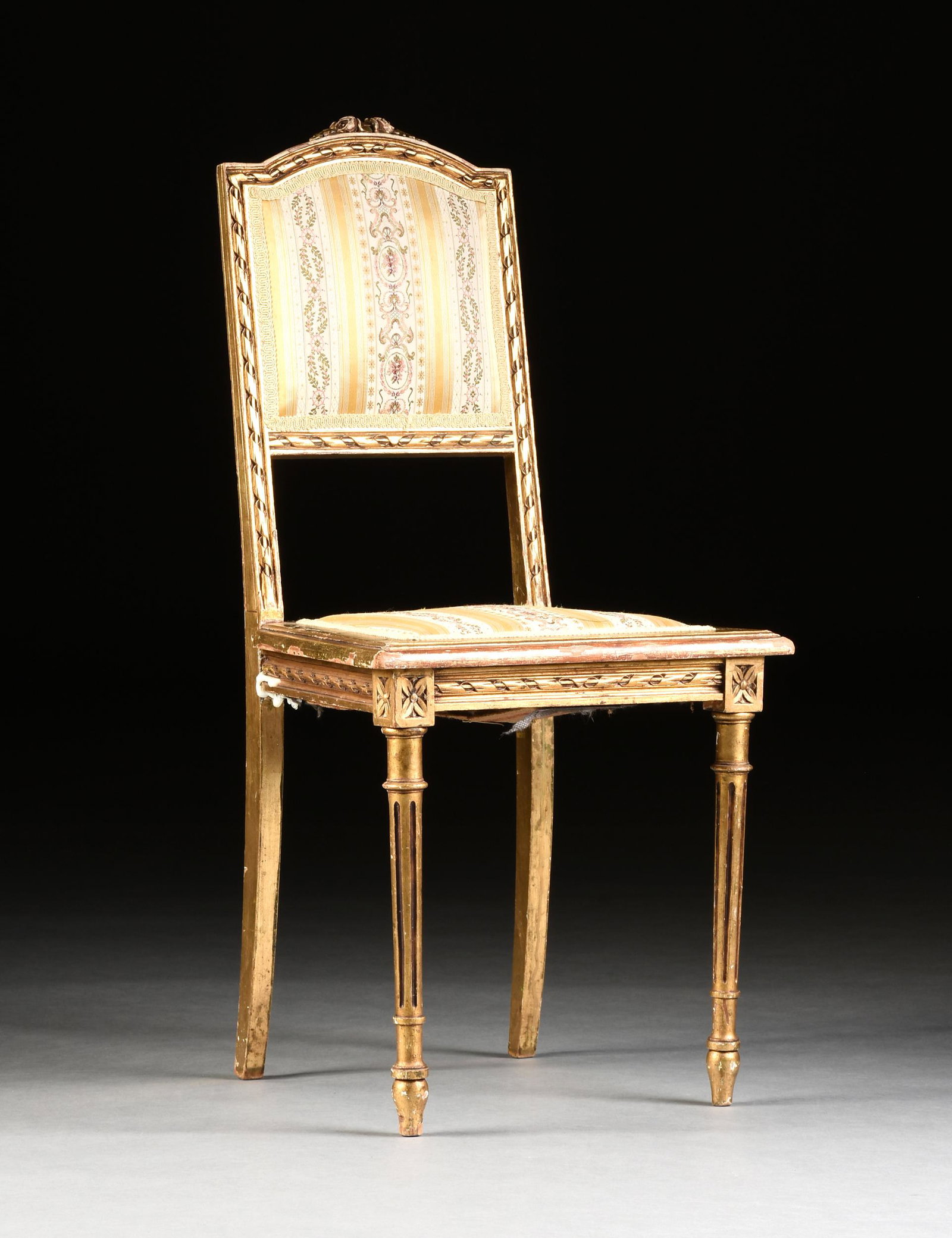 A LOUIS XVI STYLE GILT BEECH AND PINE SALON CHAIR,: A LOUIS XVI STYLE GILT BEECH AND PINE SALON CHAIR, PROBABLY ITALIAN, CIRCA 1900, the arched crest rail with carved flower blossoms, over a ribbon twist carved back, centering an arched square upholste