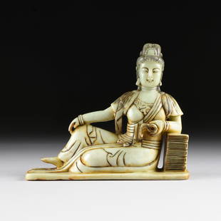 AN ASIAN CARVED SOAPSTONE RECLINING FIGURE OF GUANYIN,: AN ASIAN CARVED SOAPSTONE RECLINING FIGURE OF GUANYIN, LATE 20TH CENTURY, reading a sacred text, she leans against a stack of books. Height: 9" Width: 10 1/2"