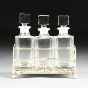 AN AMERICAN CRYSTAL AND SILVER PLATE THREE BOTTLE: AN AMERICAN CRYSTAL AND SILVER PLATE THREE BOTTLE LIQUOR SET, E.G. WEBSTER & SON, BROOKLYN, NEW YORK, CIRCA 1940, the rectangular silver plate frame with stepped acanthus scroll sides framing cast