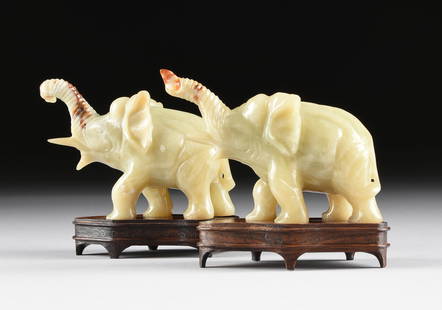 A PAIR OF CHINESE MOTTLED CELADON GREEN JADE ELEPHANTS,: A PAIR OF CHINESE MOTTLED CELADON GREEN JADE ELEPHANTS, 20TH CENTURY, each of a mottled pale celadon jade with russet brown inclusions, modeled in a walking position with reeded and raised trunks