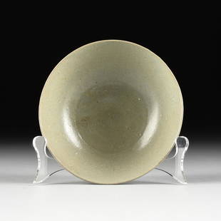 A KOREAN CELADON GLAZED EARTHENWARE BOWL, IN THE GORYEO: A KOREAN CELADON GLAZED EARTHENWARE BOWL, IN THE GORYEO DYNASTY STYLE, 18TH/19TH CENTURY, a provincial hand-thrown bowl with single incised circle and central raised boss, raised on a subtle circular