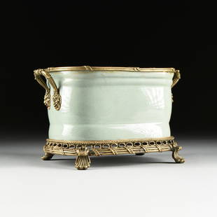 A LOUIS XVI STYLE BRONZE MOUNTED CRACKLED CELADON: A LOUIS XVI STYLE BRONZE MOUNTED CRACKLED CELADON PORCELAIN JARDINIÈRE, LATE 20TH CENTURY, of rounded rectangular form and a flat ribbon and leaf wrapped reeding cast rim on a paired tapering